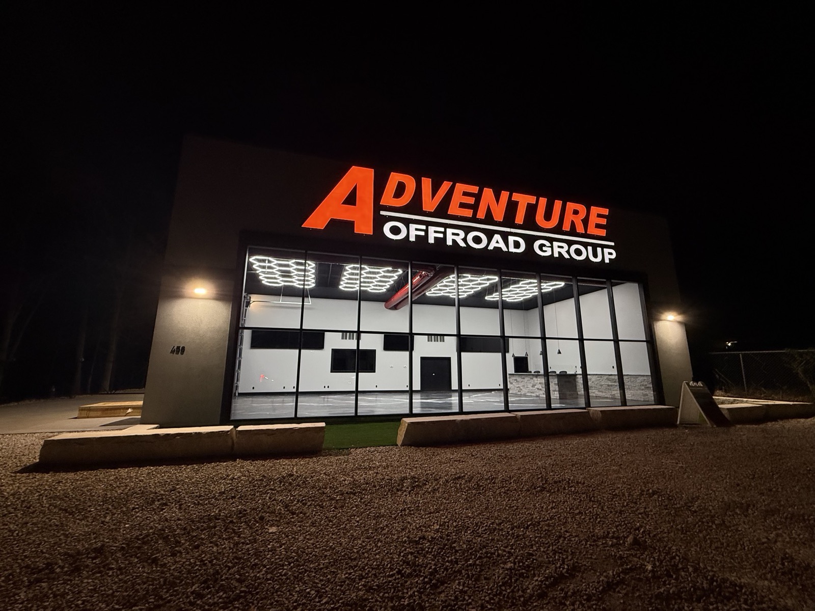 Commercial showroom at night with its lit sign and hexagon LED lighting glowing through the full-glass storefront, built by Ireland Construction