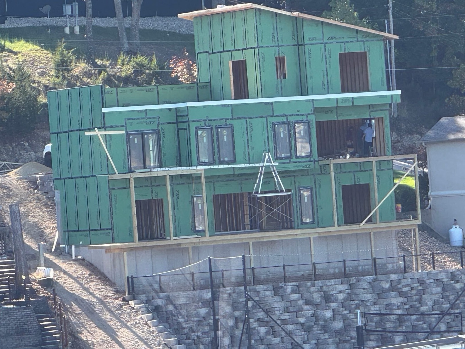 Multi-level lakefront home under construction above tiered stone retaining walls at Lake of the Ozarks, built by Ireland Construction