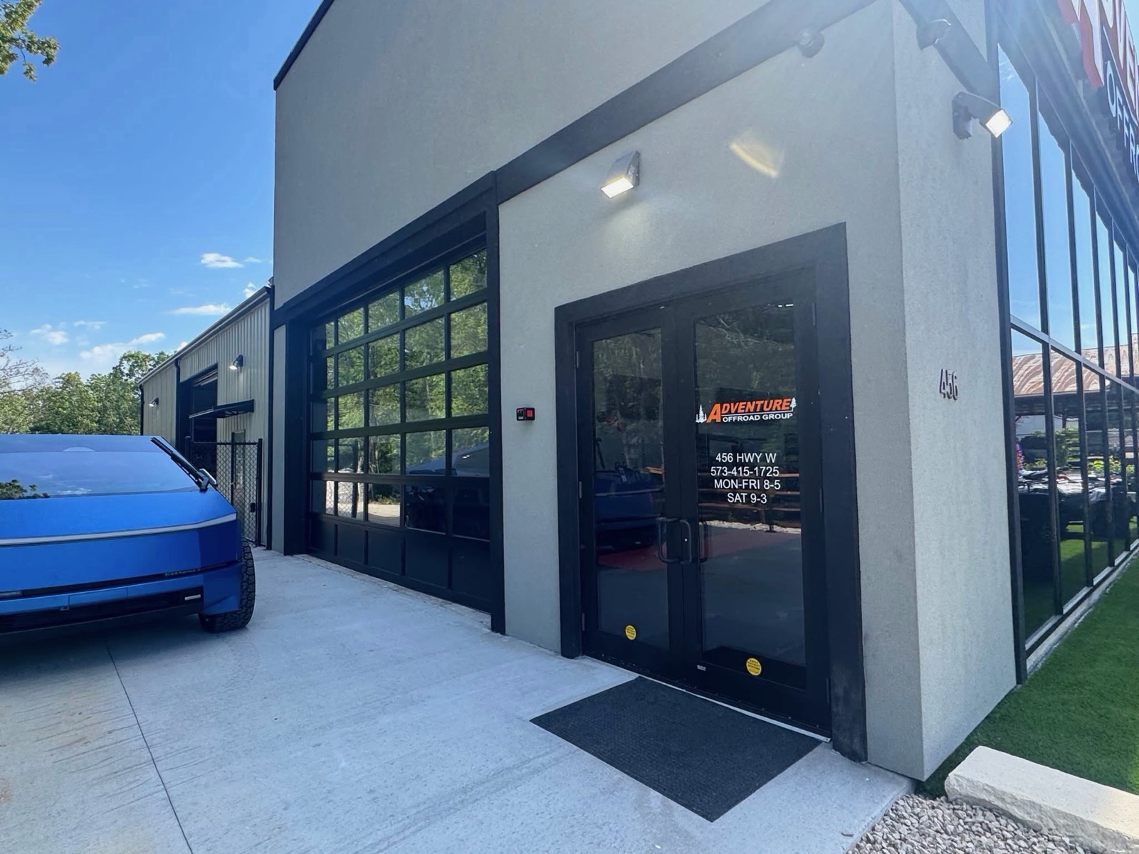 Finished modern storefront with gray stucco, black trim, and a glass-panel garage door by Ireland Construction