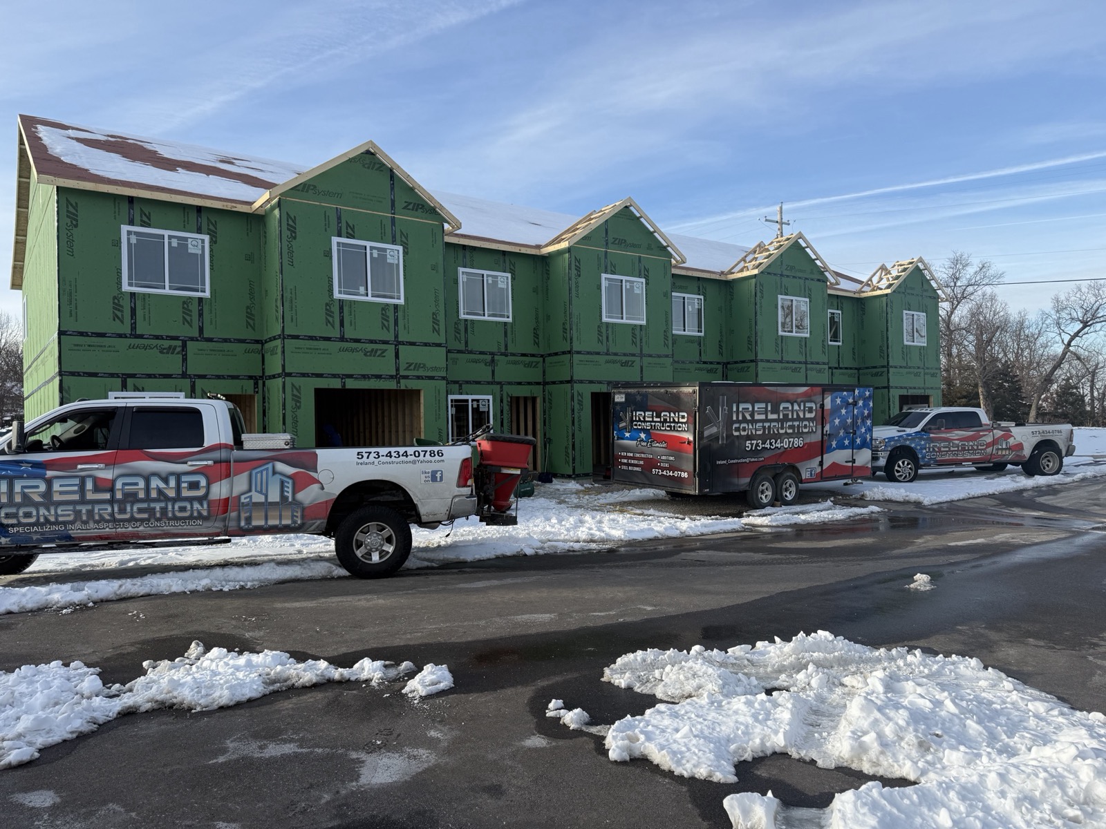 Ireland Construction trucks and trailer outside a row of townhomes under construction on a snowy street