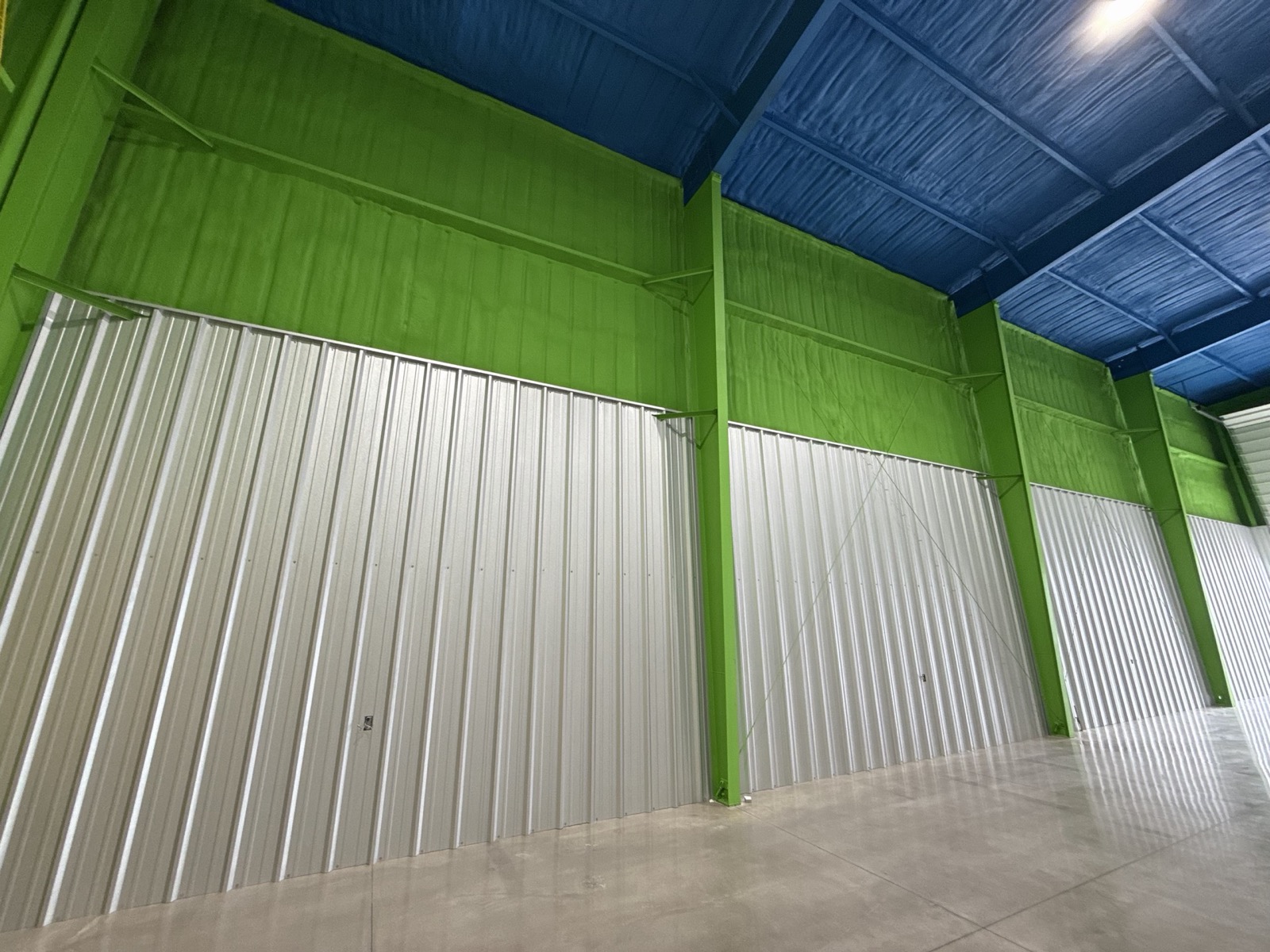 Metal building interior with spray-foam coated steel framing, insulated roof deck, and polished concrete floor by Ireland Construction