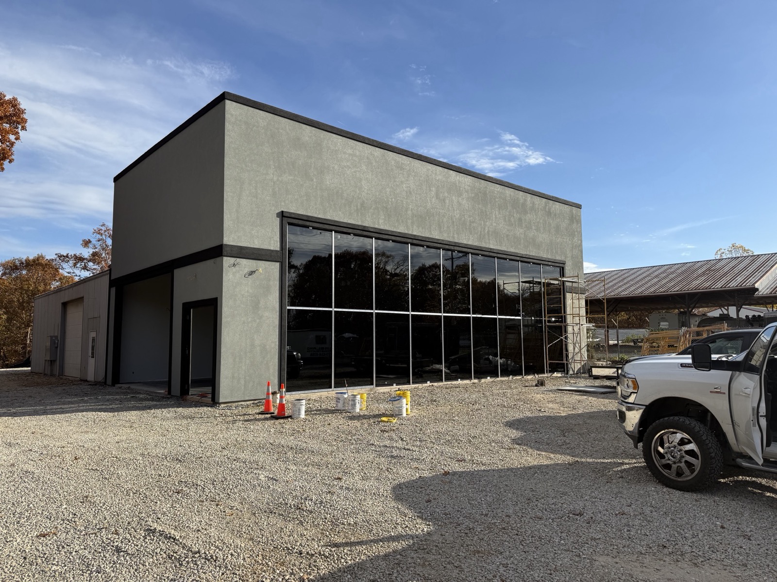 Modern flat-roof commercial building with dark stucco and a full-height glass storefront nearing completion by Ireland Construction