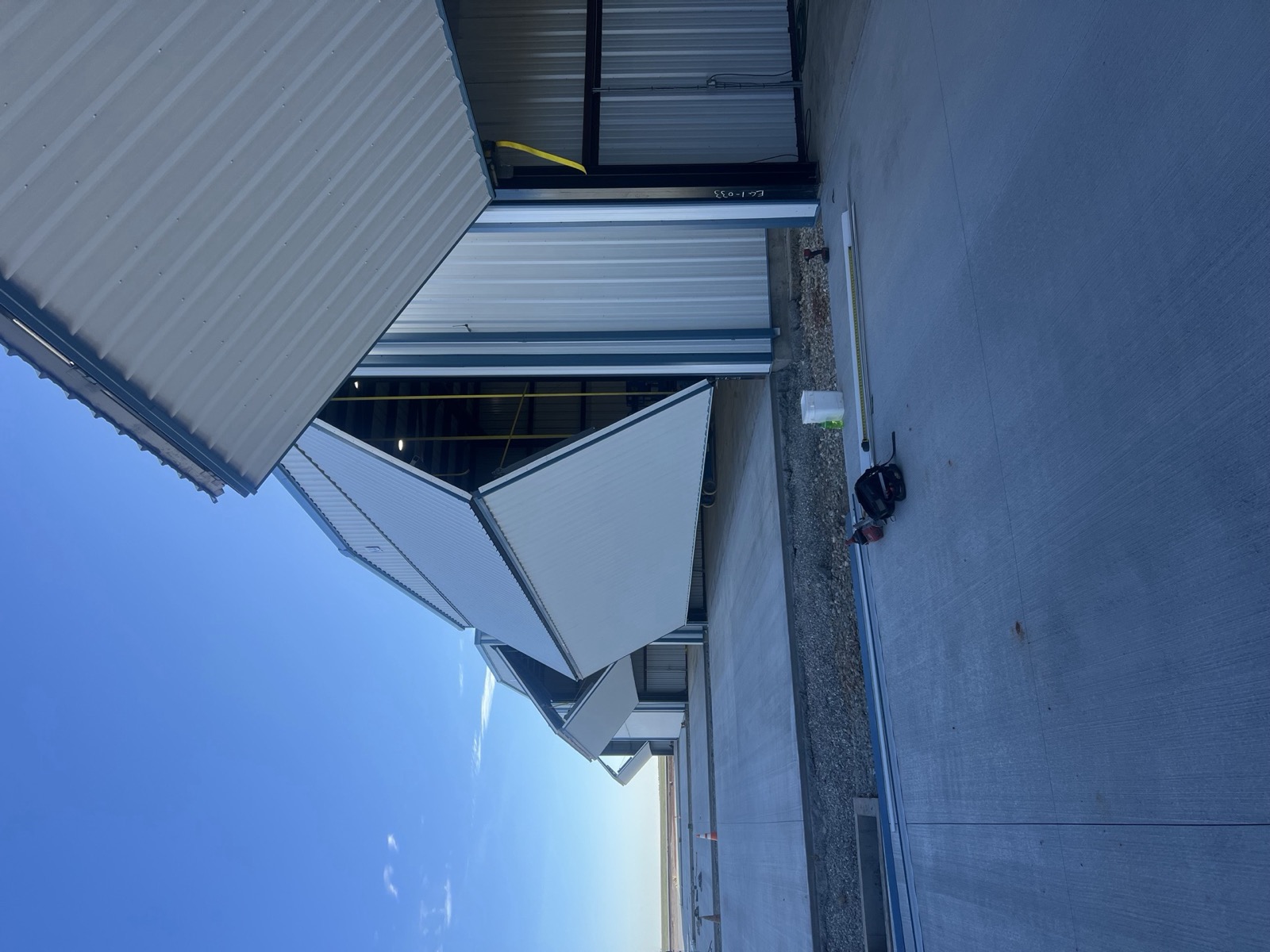 Row of metal hangars with bifold doors raised above a new concrete apron, built by Ireland Construction